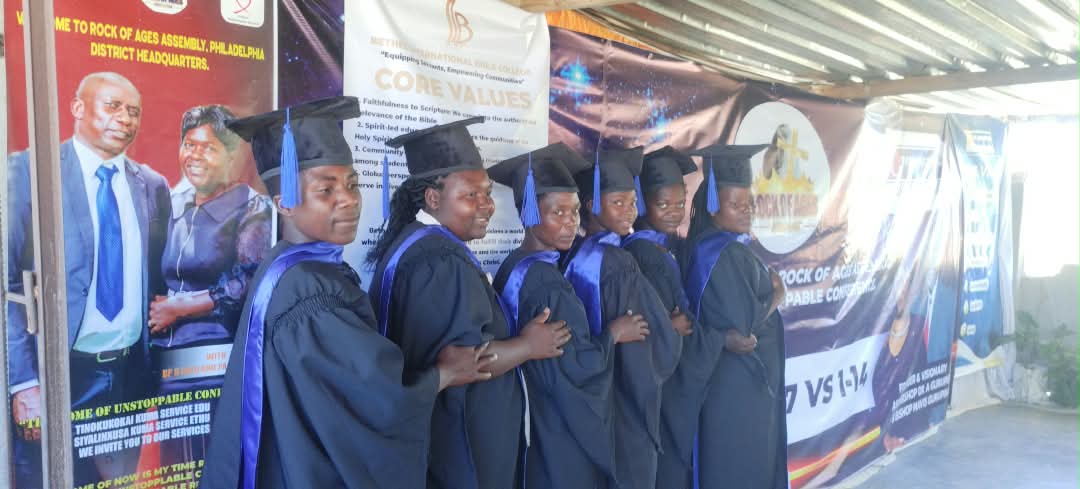 Graduates in black gowns and blue sashes standing in a line